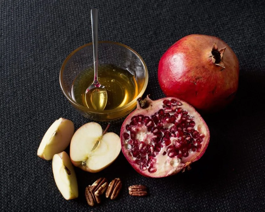 Apples and pomegranates with a bowl of honey